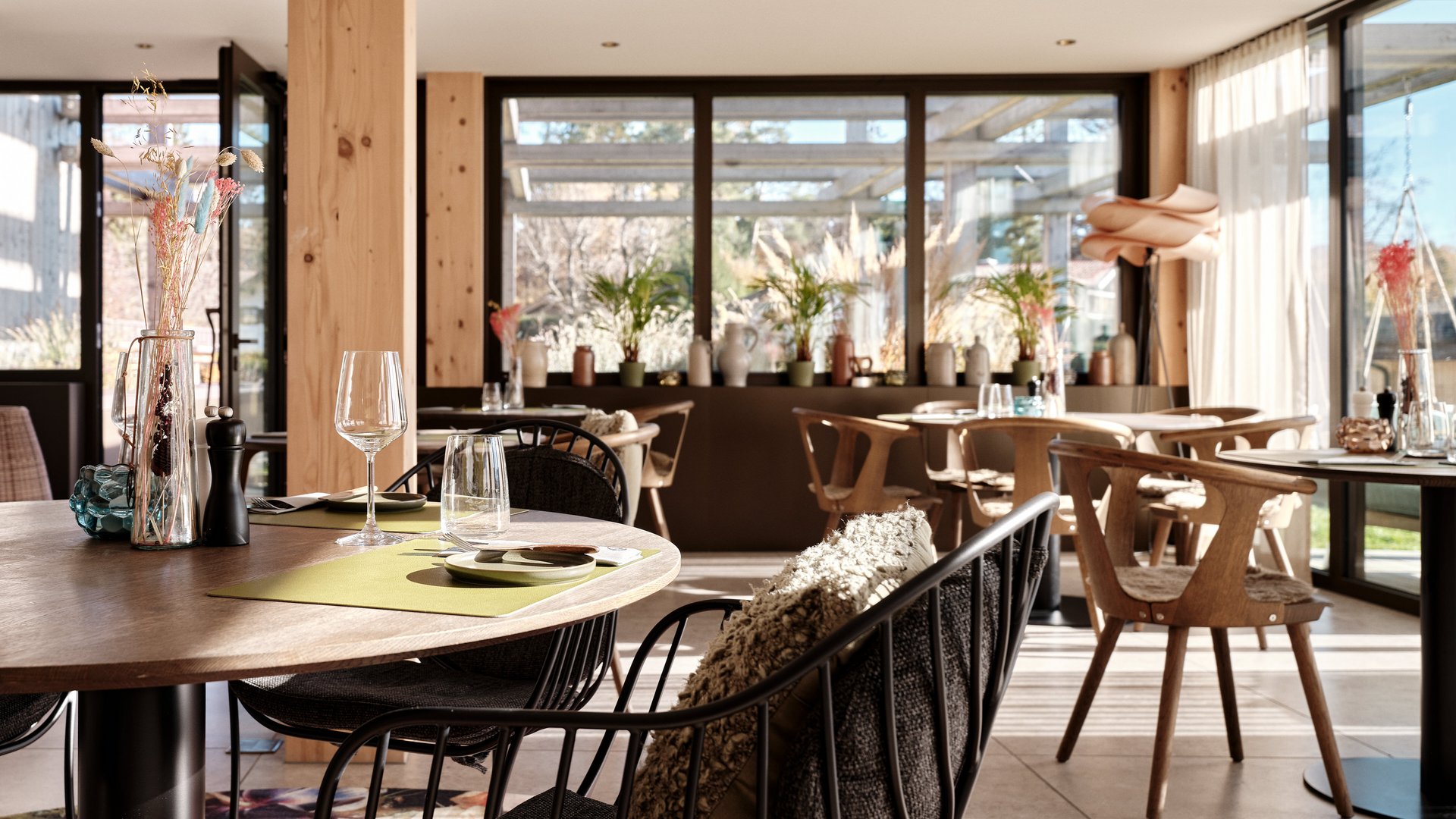 BERGEBLICK: Ihr Hotel in Bad Tölz Modern eingerichteter Speisesaal mit Holzmöbeln und großen Fenstern bei Tageslicht
