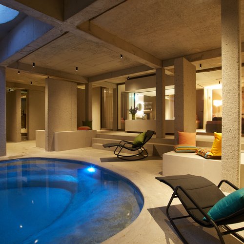 Wellness in Bad Tölz Heated indoor pool with modern lounge chairs and cushions in a spa area