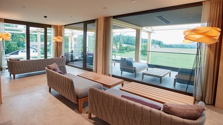 Aussicht auf Traumurlaub in Bad Tölz Moderne Lounge mit Sesseln, Sofas und großem Fenster zur Terrasse und Landschaft
