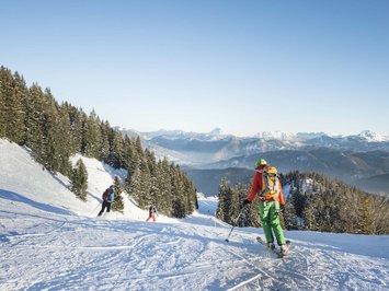 Winter bliss in Bad Tölz Skiers on snowy slope with mountains and pine trees in the background