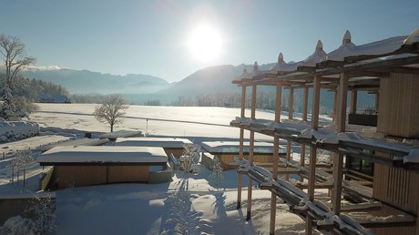 Aussicht auf Traumurlaub in Bad Tölz Schneebedeckte Häuser und Bäume bei Sonnenaufgang in einer verschneiten Landschaft
