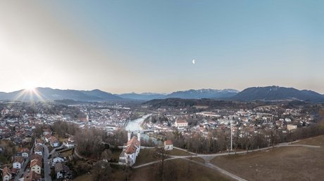 Aussicht auf Traumurlaub in Bad Tölz Panorama einer Stadt mit Fluss, Kirche, Bergen und aufgehender Sonne