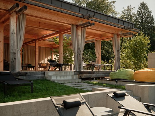 BERGEBLICK: Ihr Hotel in Bad Tölz Moderner Holzpavillon mit Vorhängen und Liegestühlen im Garten