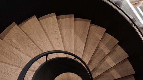 Aussicht auf Traumurlaub in Bad Tölz Spiralförmige Holztreppe mit schwarzem Geländer in modernem Innenraum