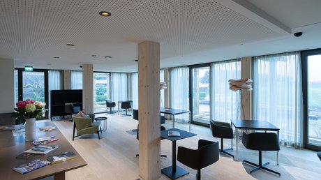Aussicht auf Traumurlaub in Bad Tölz Moderner Aufenthaltsraum mit Tischen, Stühlen und Panoramafenstern