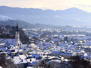 Winter bliss in Bad Tölz Snow-covered town with church and forested mountains in winter