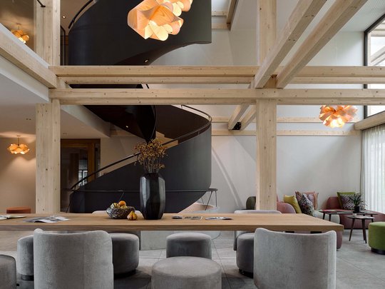 BERGEBLICK: Ihr Hotel in Bad Tölz Moderner Raum mit schwarzen Wendeltreppen und grauen Sitzmöbeln aus Holz