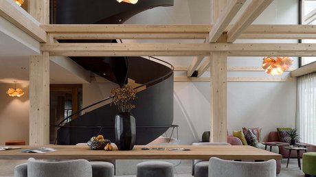 Aussicht auf Traumurlaub in Bad Tölz Moderner Raum mit schwarzen Wendeltreppen und grauen Sitzmöbeln aus Holz