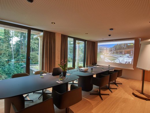 Hotel BERGEBLICK in Bavaria Modern conference room with tables, chairs, projector, and view of forest outside