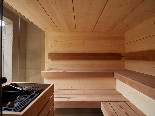 Dein Retreat im BERGEBLICK Innenansicht einer modernen Holzsauna mit Bänken und Saunaofen
