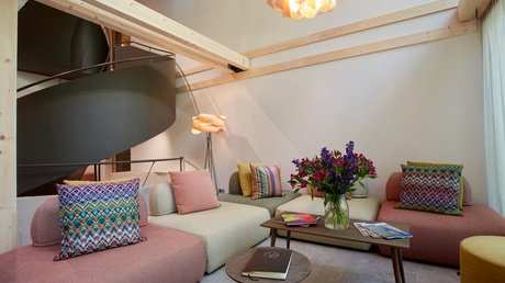 Aussicht auf Traumurlaub in Bad Tölz Modern eingerichtetes Wohnzimmer mit bunten Kissen, Holzdecke und Blumenvase auf dem Tisch