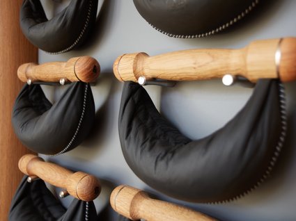 Dein Aktivurlaub im Hotel mit Fitnessstudio in Bayern Schwarze Ledertaschen an Holzgriffen an der Wand