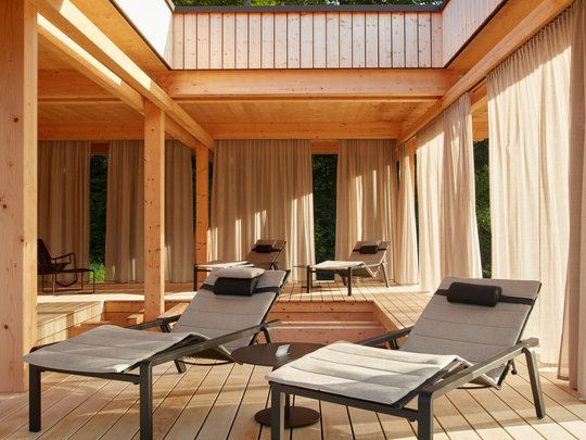 Dein Retreat im BERGEBLICK Moderne Holzterrasse mit gepolsterten Liegestühlen und Vorhängen