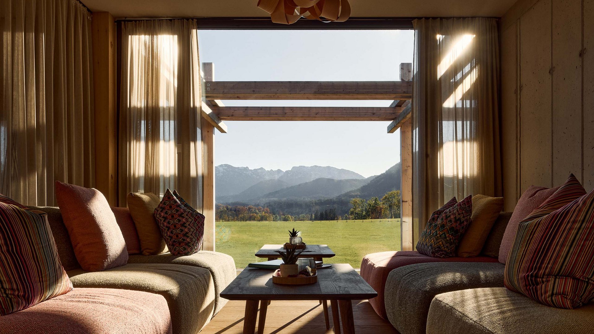 Hotel BERGEBLICK in Bavaria Cozy living room with view of green field and mountains through large window