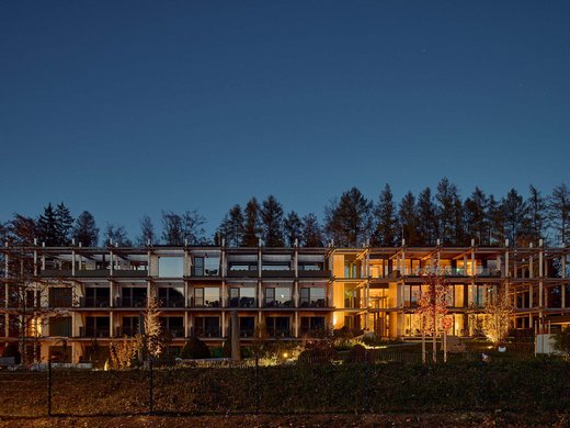 BERGEBLICK: dein Tagungshotel in Bayern Modernes mehrstöckiges Gebäude bei Nacht mit beleuchteten Innenräumen und Bäumen im Hintergrund