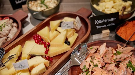 Aussicht auf Traumurlaub in Bad Tölz Verschiedene Käsesorten und geräucherter Fisch auf Holzplatten mit Kräuterbutter