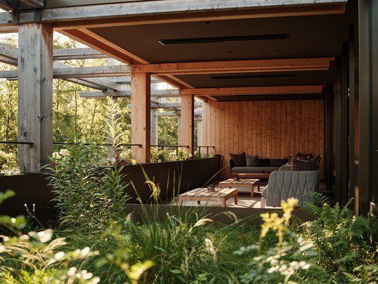 BERGEBLICK: Ihr Hotel in Bad Tölz Gemütliche überdachte Terrasse mit Holzverkleidung und Sitzmöbeln umgeben von Pflanzen