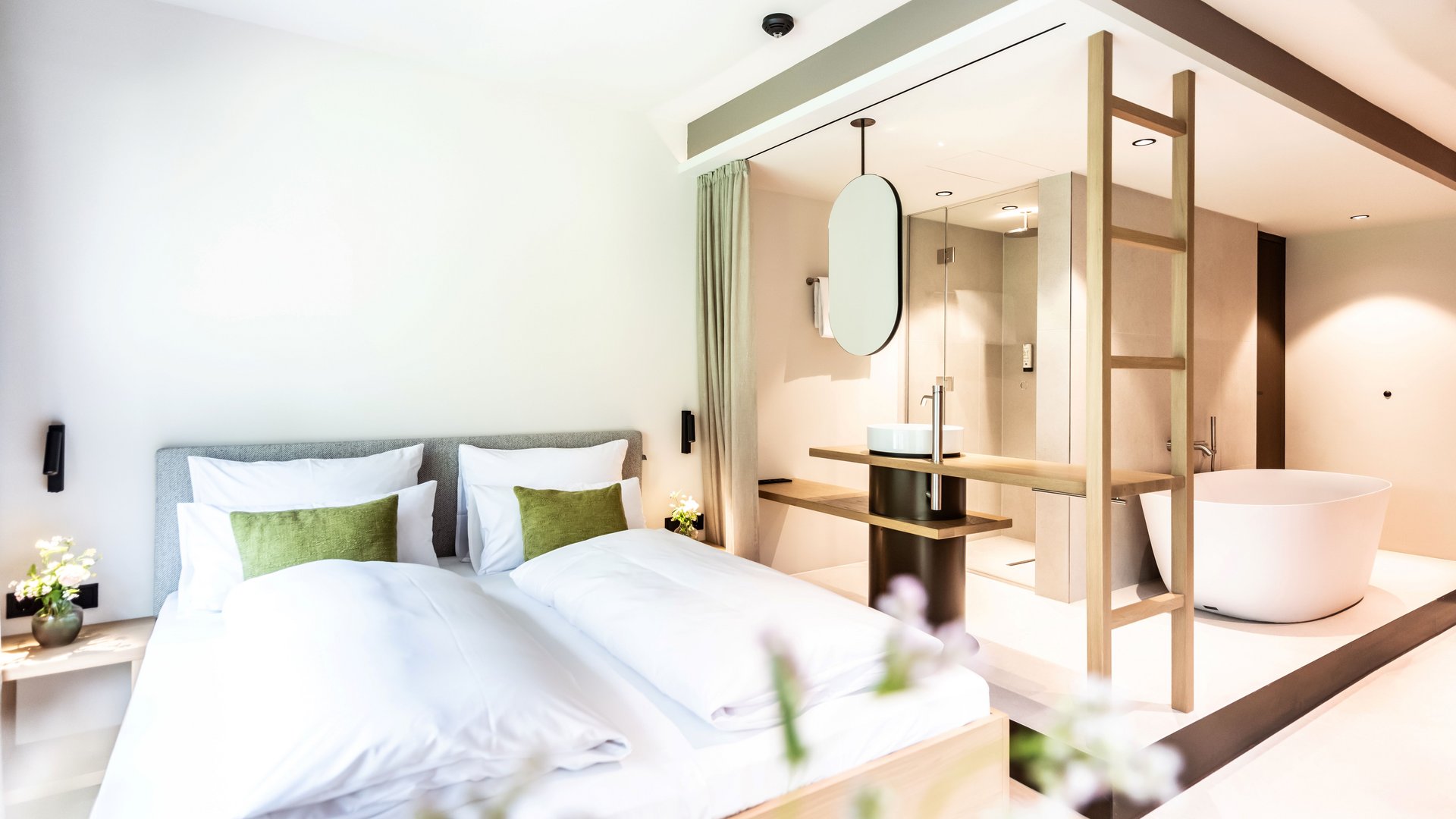 BERGEBLICK: Ihr Hotel in Bad Tölz Modernes Schlafzimmer mit Doppelbett und freistehender Badewanne im offenen Badezimmer