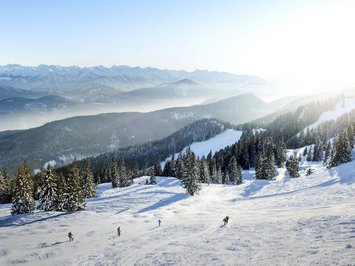Winter bliss in Bad Tölz Snow-covered mountains with skiers under a sunny sky