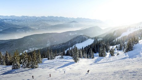Aussicht auf Traumurlaub in Bad Tölz Verschneite Berge mit Skifahrern und sonnigem Himmel
