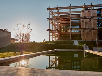 Your holiday in nature in Bavaria: Hotel BERGEBLICK Modern wooden architecture by a calm pool at sunset