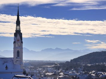 Winter bliss in Bad Tölz Church tower over snow-covered village with mountains and blue sky in the background