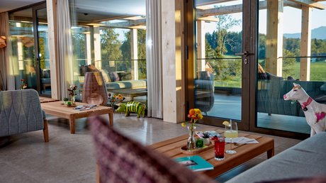 Aussicht auf Traumurlaub in Bad Tölz Gemütlicher Wohnraum mit Holzmöbeln und großer Glasfront zur Terrasse und Landschaft
