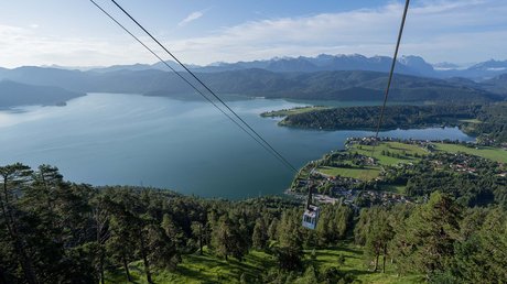 Aussicht auf Traumurlaub in Bad Tölz Seilbahn über bewaldeten Hügel mit Blick auf See und Berge im Hintergrund