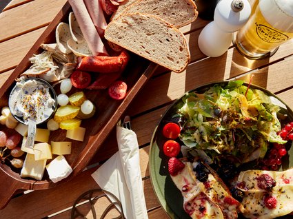 Bad Tölz: hotel with regional breakfast Platter with meats, cheese, bread, salad, and a glass of beer on wooden table