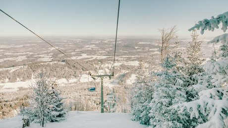 Aussicht auf Traumurlaub in Bad Tölz Blick auf schneebedeckten Skilift und verschneite Bäume im Winter