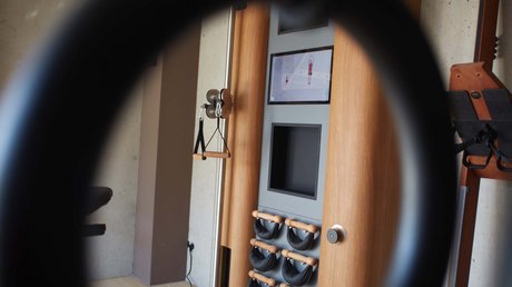 Aussicht auf Traumurlaub in Bad Tölz Blick durch einen Ring auf ein modernes Trainingsgerät mit Bildschirm und Griffen