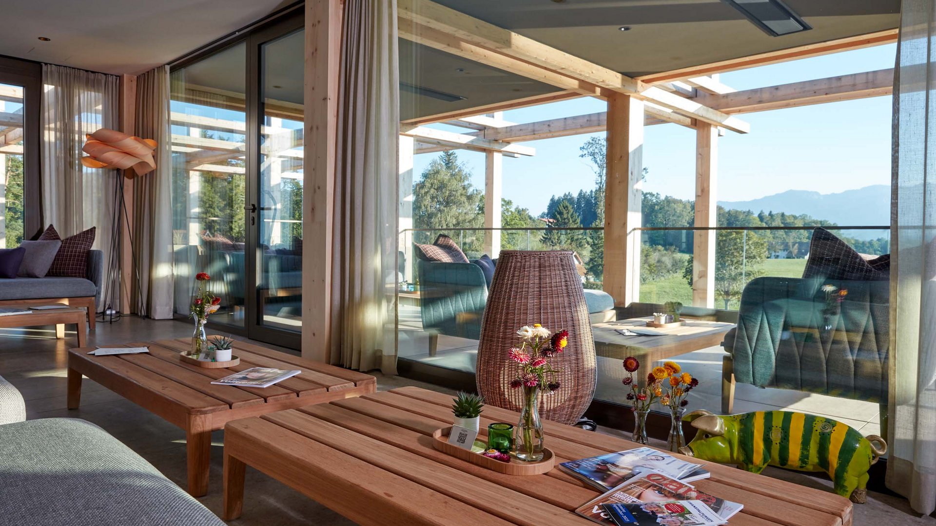Your lounge for business & indulgence Cozy living area with wooden tables, decorations, and view of balcony and nature