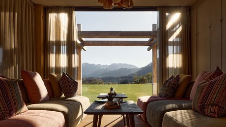 Aussicht auf Traumurlaub in Bad Tölz Gemütliches Wohnzimmer mit Aussicht auf grüne Wiese und Berge im Hintergrund