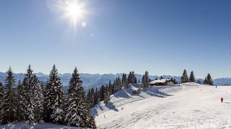 Aussicht auf Traumurlaub in Bad Tölz Winterlandschaft mit schneebedeckten Bäumen, Bergen und Sonne am klaren Himmel