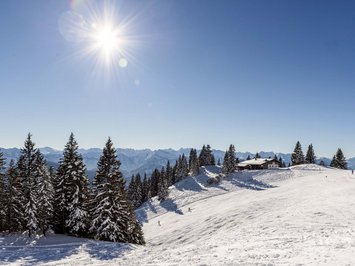 Winter bliss in Bad Tölz Winter landscape with snow-covered trees, mountains, and sun in a clear sky