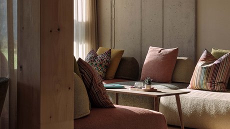 Aussicht auf Traumurlaub in Bad Tölz Gemütliches Wohnzimmer mit Sofas, bunten Kissen und Holzlampe