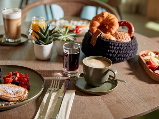 BERGEBLICK: Ihr Hotel in Bad Tölz Frühstückstisch mit Kaffee, Brötchen, Pancakes und verschiedenen Getränken