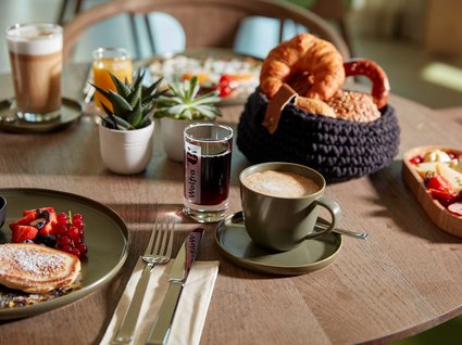 Bad Tölz: hotel with regional breakfast Breakfast table with coffee, bread rolls, pancakes, and assorted drinks