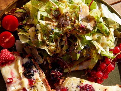 Bad Tölz: hotel with regional breakfast Salad with cheese bread and berries on a plate, next to a glass of beer