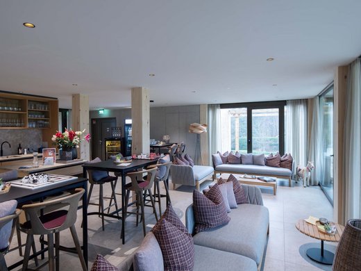 BERGEBLICK: dein Tagungshotel in Bayern Moderne Lounge mit Sofas, Tischen, Stühlen und großen Fenstern