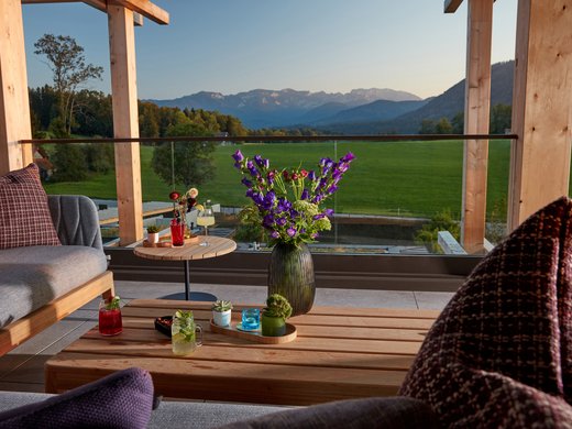 Your lounge for business & indulgence Terrace with sofa, table, flowers and mountain view at sunset