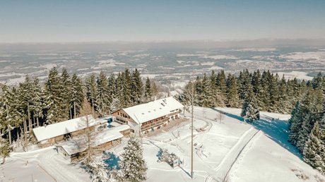 Aussicht auf Traumurlaub in Bad Tölz Winterliche Alm im Schnee mit Blick auf verschneite Landschaft und Wald