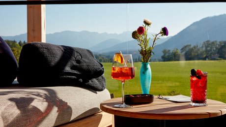 Aussicht auf Traumurlaub in Bad Tölz Getränke und Blumen auf Tisch mit Bergblick am sonnigen Tag