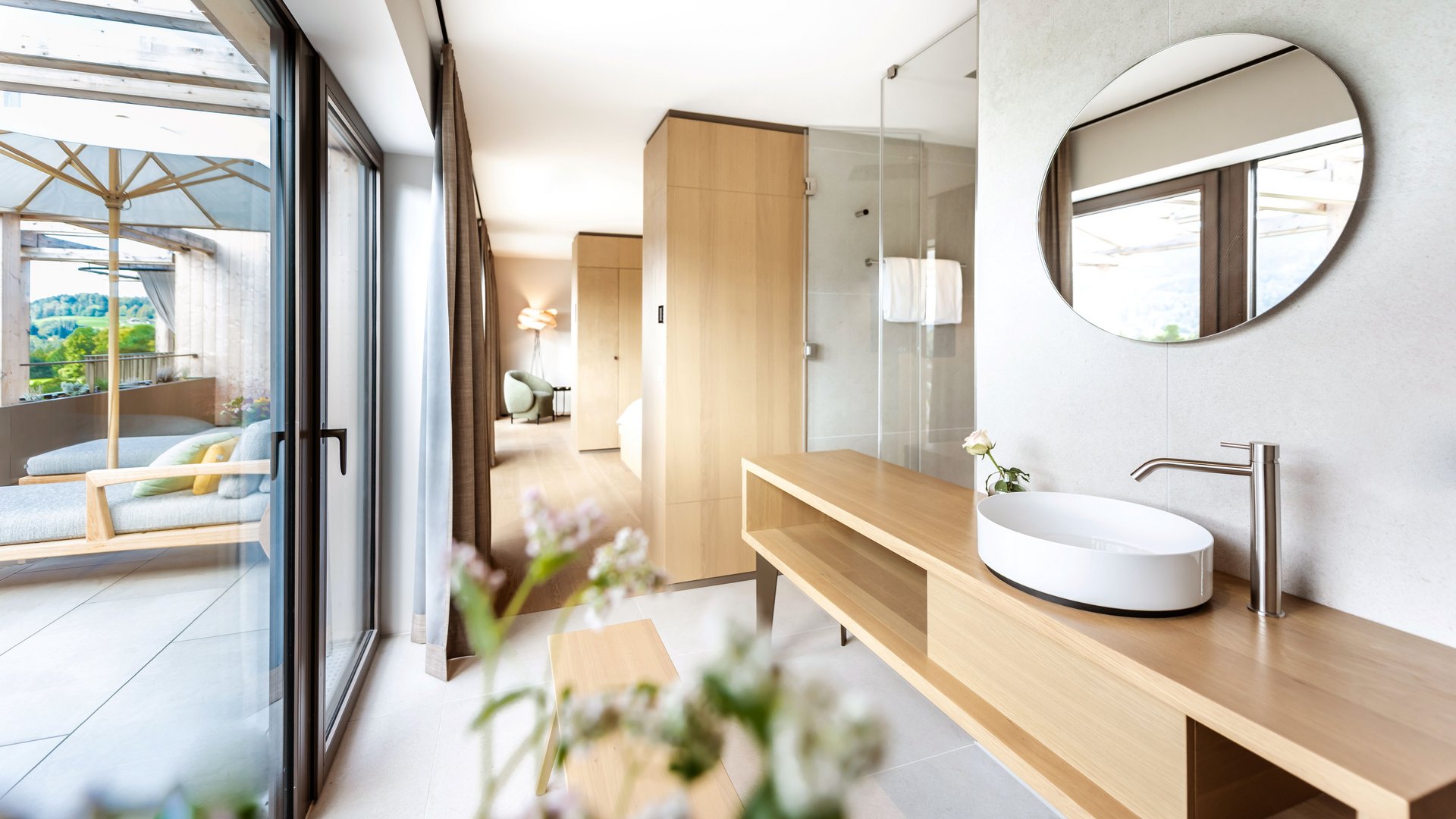 Sonja Sindlhauser Modern hotel bathroom area with wooden sink counter and terrace seating area